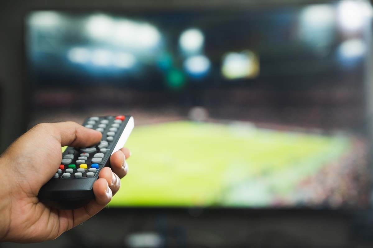 Young Man Holding Television Remote Control Watching Football Pr