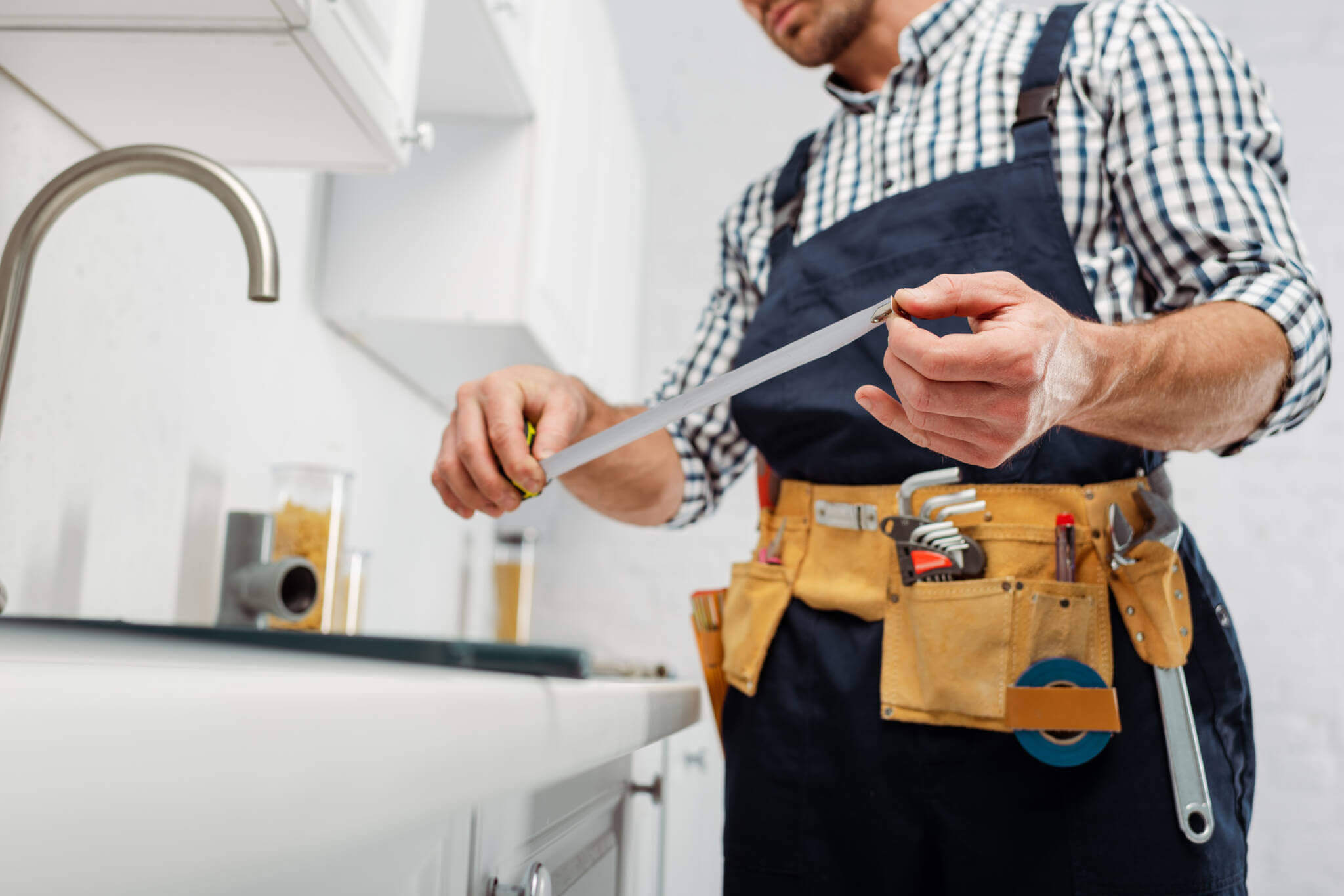 Cropped View Of Plumber Holding Industrial Measuring Tape Near Faucet In Kitchen